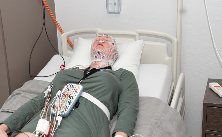 middle aged woman having her brain waves measured in the sleep lab (polysomnography)